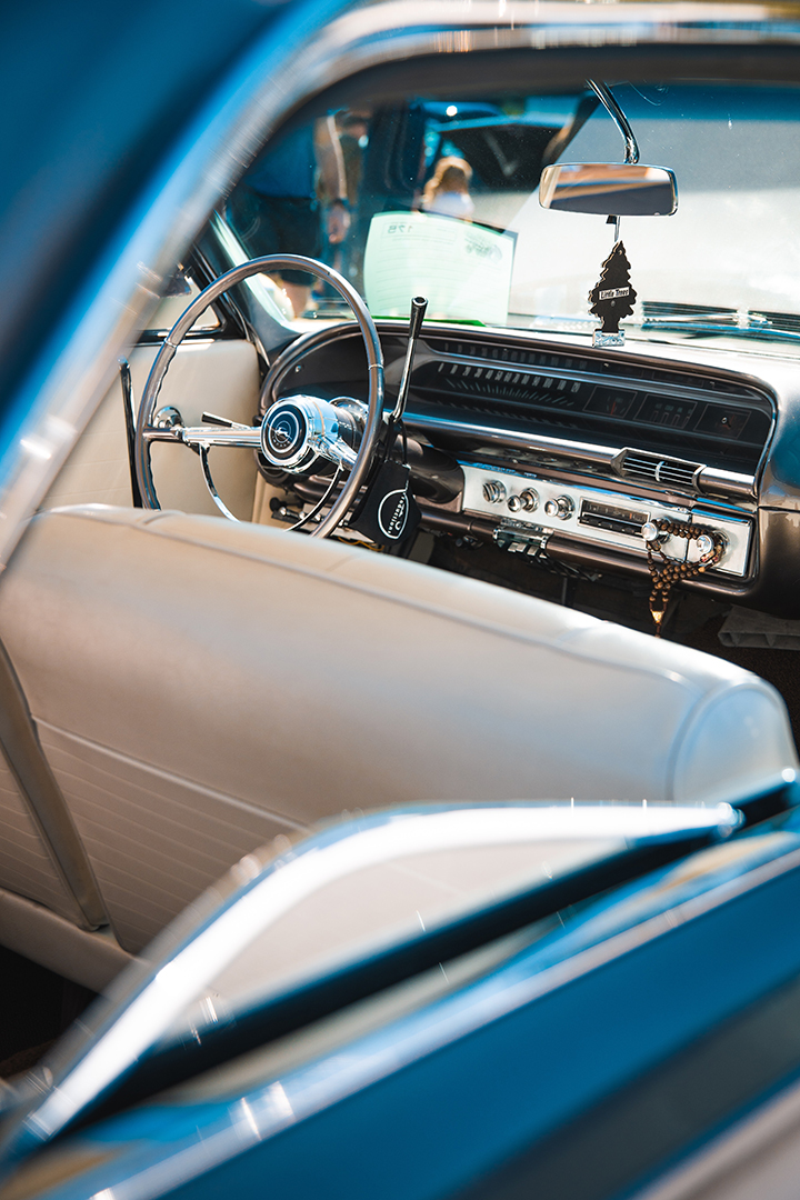 Picture of a restored classic car interior complete with a shiny chrome steering wheel and leather seats.