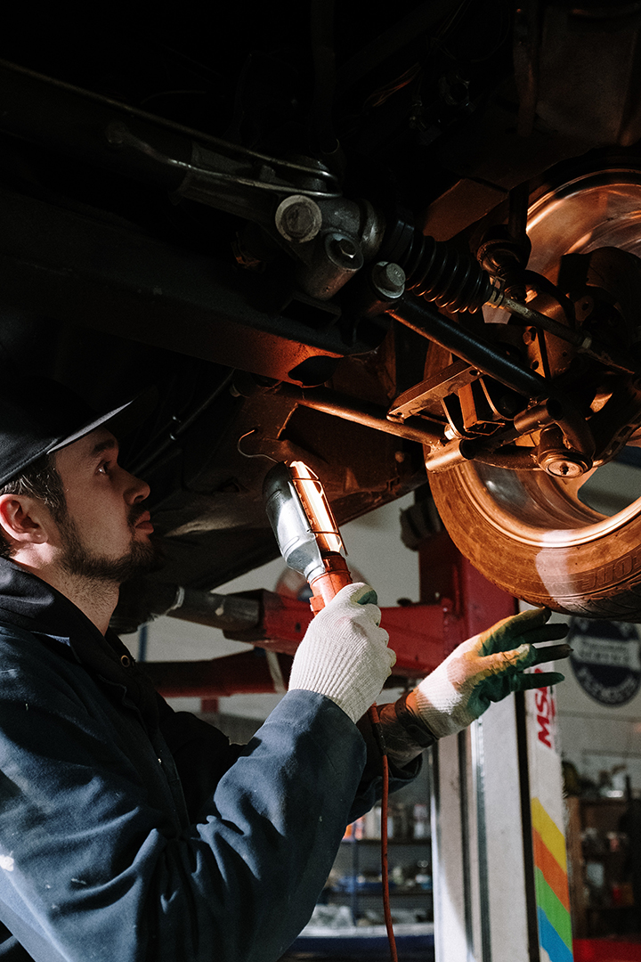 Picture of Bob holding a light inspecting the condietion of a car in his shop.