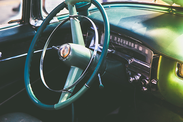 Picture of a classic car steering wheel and dashboard.